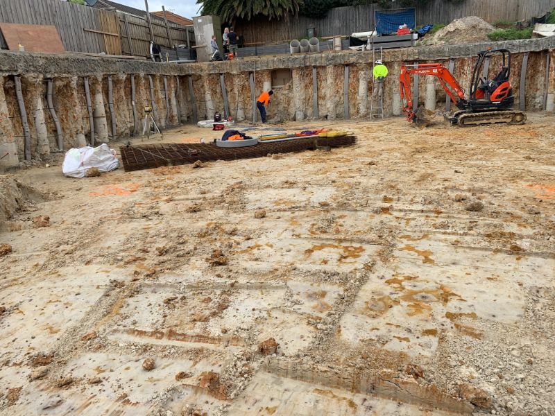 Basement excavation site showing groundwater management with secant piling retaining walls and drainage preparation